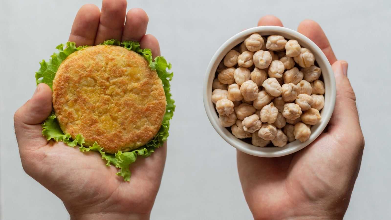 In one hand, a cutlet and a leaf of lettuce, in the other a bowl full of nuts